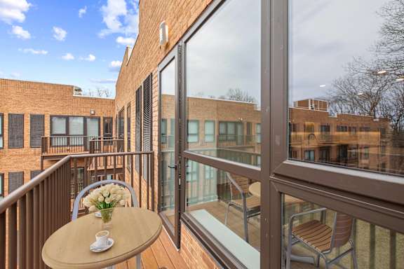 A balcony with a table and chairs overlooking a building.