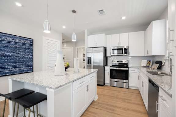 A modern kitchen with white cabinets and stainless steel appliances.