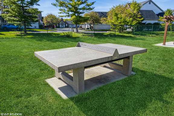 A concrete table in a grassy area with a house in the background at Island Club Apartments, Columbus, OH, 43235