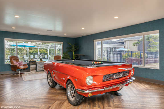 a pool table in a living room with a red car