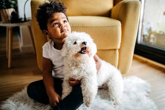 a young child holding his pet dog insinde their home