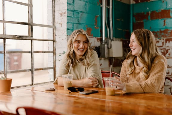 two women sitting at a table with drinks