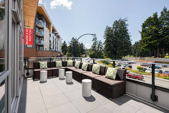 a large balcony with couches and a view of a parking lot and a building