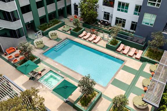 A pool with chairs and a building in the background.