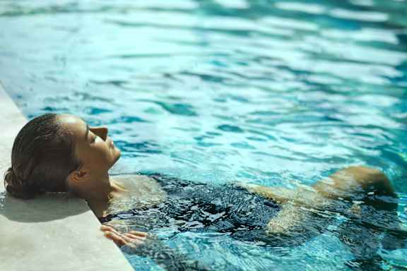 A woman is floating on her back in a pool.
