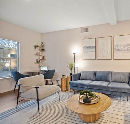 A living room with a grey sofa, a wooden coffee table, and a blue chair.