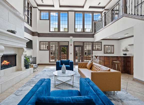 A large, well-lit living room with a fireplace and a blue sofa.
