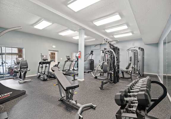 A gym with a variety of equipment including treadmills, weights, and exercise machines.