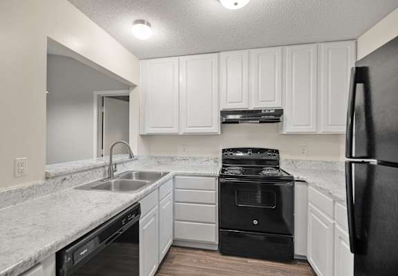 A kitchen with white cabinets and black appliances.