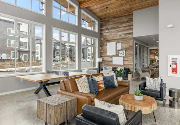 a living room with a brown leather couch and a wooden coffee table in front of a large