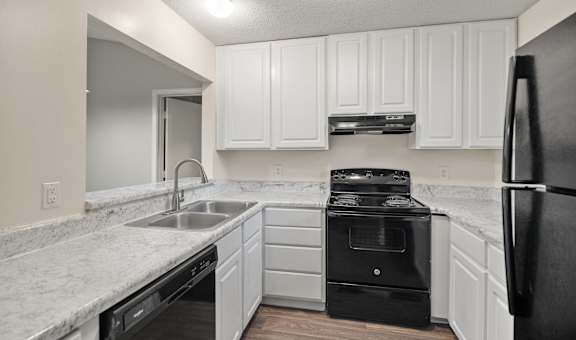 A kitchen with white cabinets and black appliances.