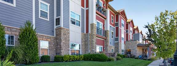 A row of apartment buildings with a sidewalk in front.