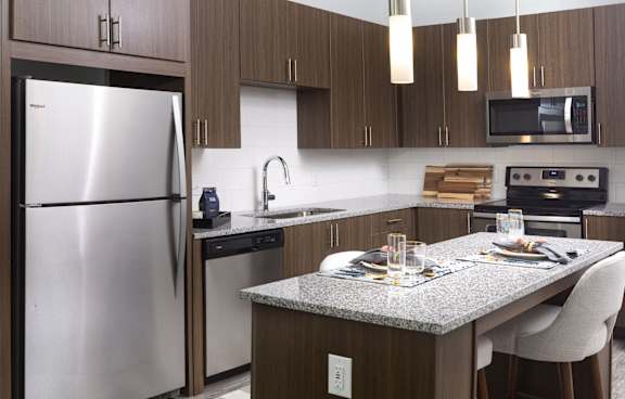 A modern kitchen with a stainless steel refrigerator and a granite countertop.