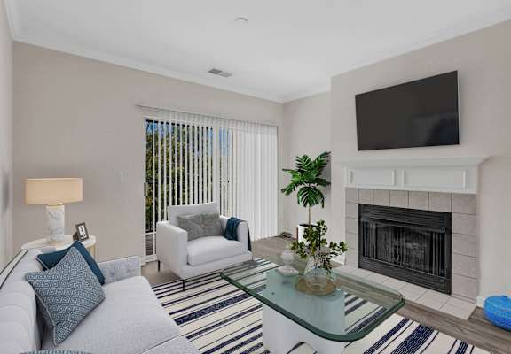 A living room with a fireplace and a television mounted above it.