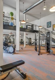 a gym with weights and cardio machines and a spiral staircase