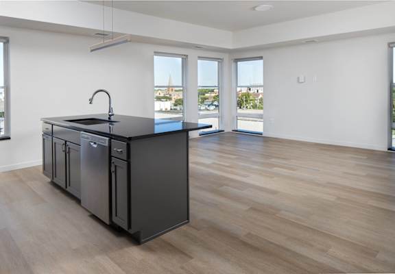an open kitchen and living room with a large window and a black counter top at Riverhouse Apartments, Fargo, North Dakota