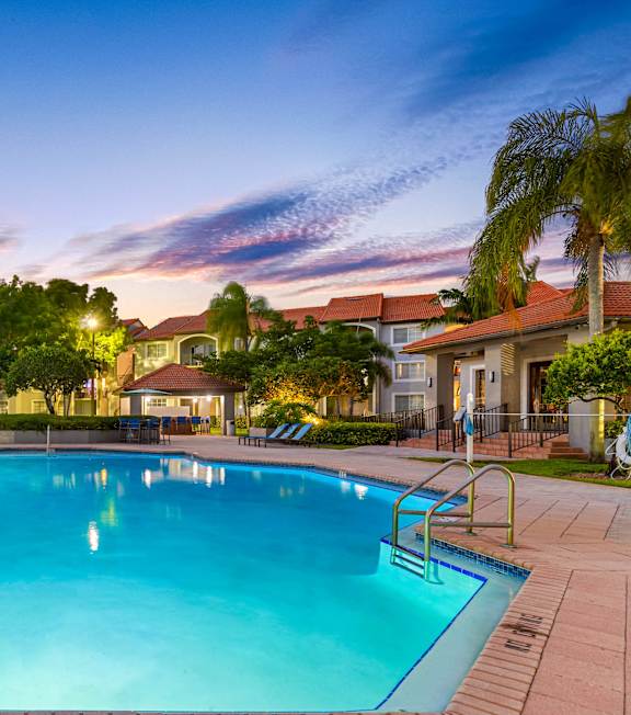 A large swimming pool surrounded by palm trees and buildings.