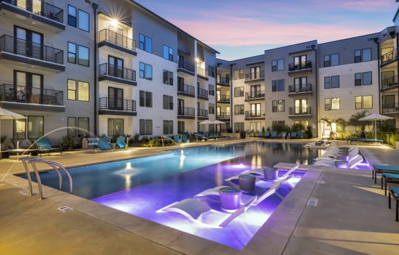 an apartment swimming pool with purple lights at night