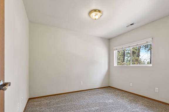 a bedroom with white walls and a window