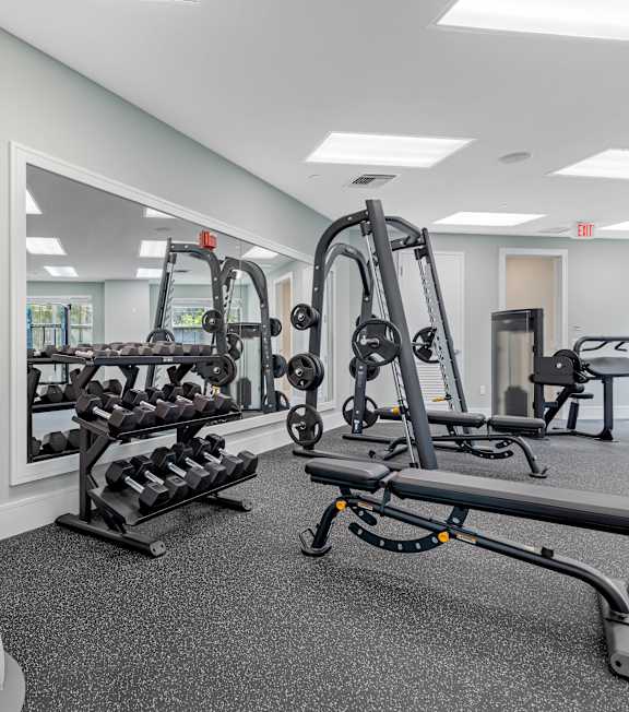 A gym with a mirror, weights, and exercise equipment.