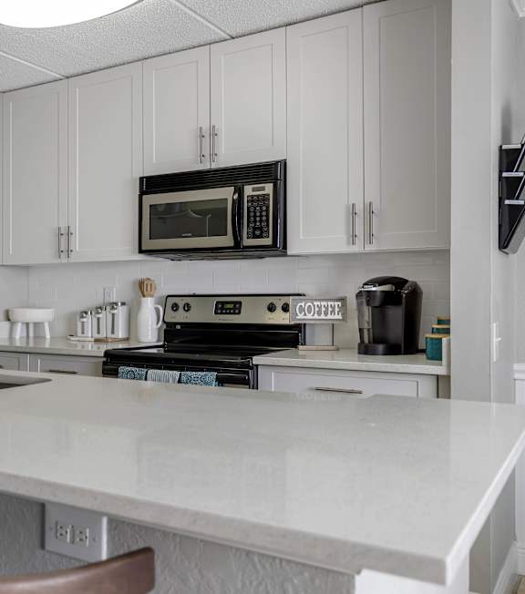 A kitchen with a white countertop and a black refrigerator.