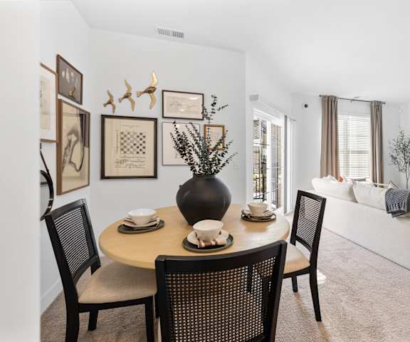 A dining room with a table set for two and a couch in the background.
