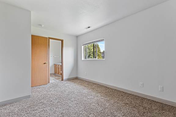 a bedroom with white walls and carpet
