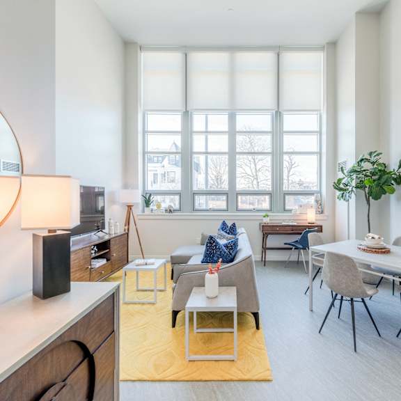 A living room with a grey couch, a white table, and a yellow rug.