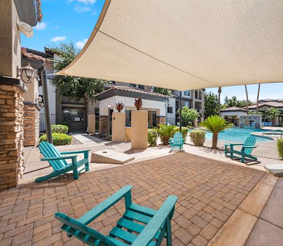 A patio with a white umbrella and blue chairs.
