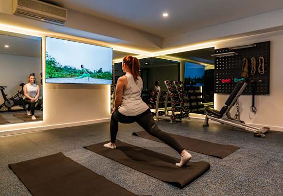 a woman practicing yoga in a gym with a tv