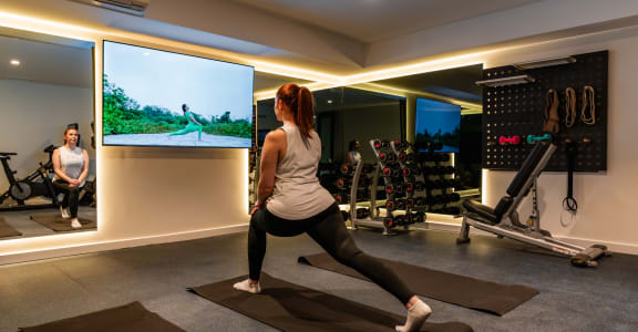 a woman practicing yoga in a gym with a tv