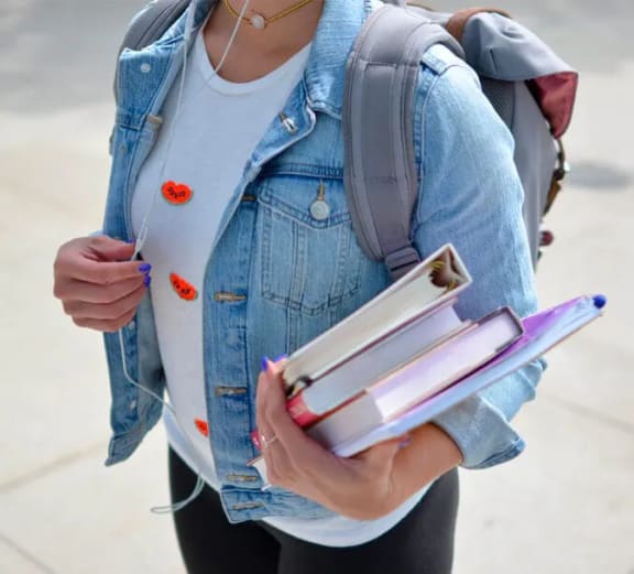 a woman carrying books and a backpack