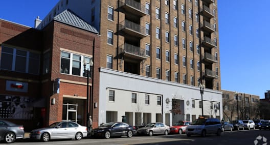 A tall building with a brown facade stands next to a white building with a black roof.