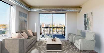 A living room with a couch, chairs, and a coffee table at The Bessemer at Seward Commons Apartments, Minnesota, 55404
