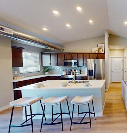 A modern kitchen with a bar area and a living room with a couch and a coffee table.