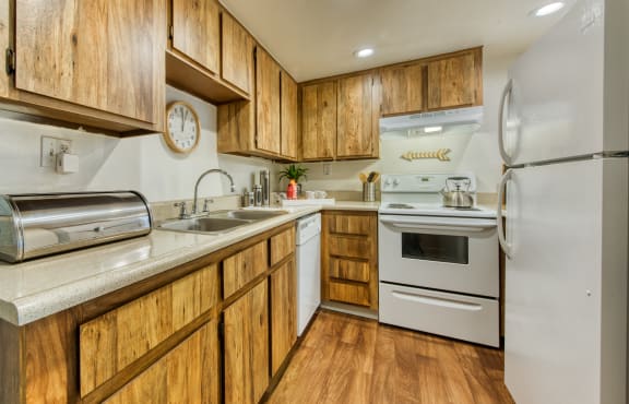 a kitchen with white appliances and wooden cabinets at Connect on Northern Apartments, Glendale, AZ