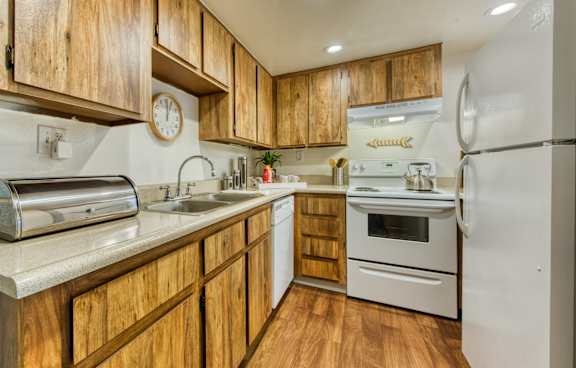 A kitchen with wooden cabinets and a white refrigerator at Connect on Northern Apartments, Glendale 85301