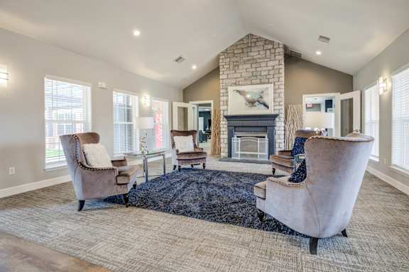 A living room with a stone fireplace and a large chair.