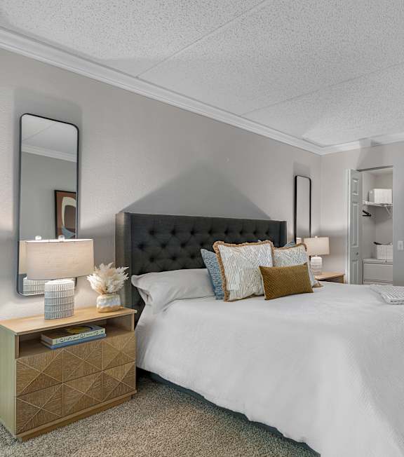 A bedroom with a large bed and a dresser with a mirror above it.