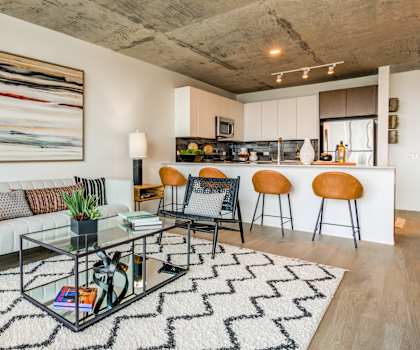 A modern living room with a glass coffee table and a large abstract painting on the wall.