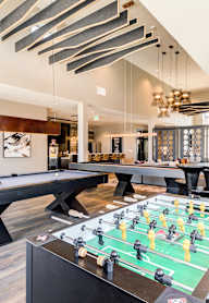 A foosball table is in the middle of a room with a pool table and a bar.