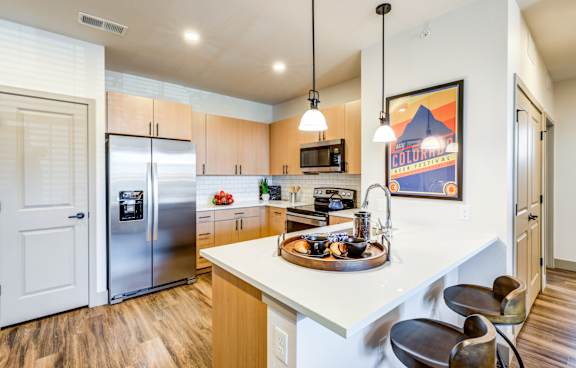 A kitchen with a refrigerator, microwave, and oven.