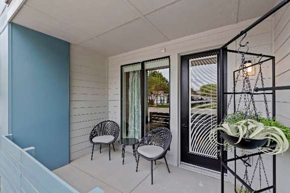A balcony with two chairs and a table with a plant on it.