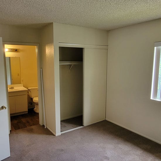 an empty bedroom with a large window and a bathroom in the background