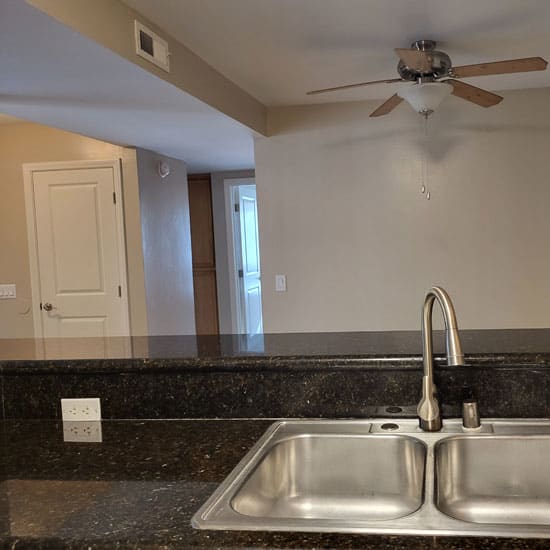 a kitchen with a sink and a ceiling fan