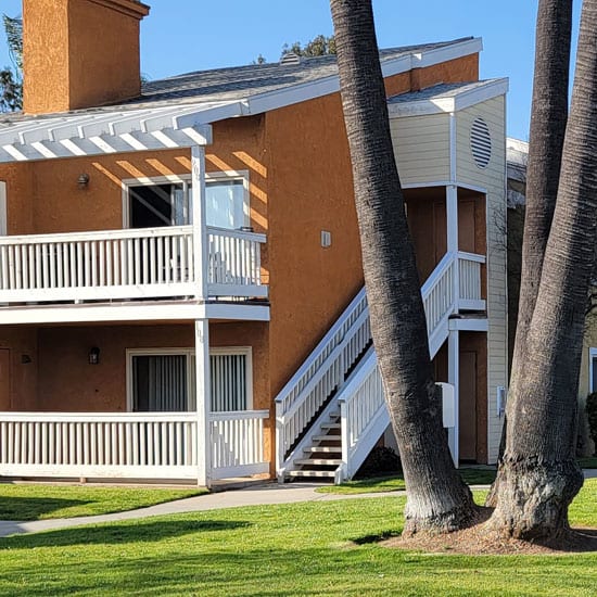 a building with a staircase and two palm trees in front of it