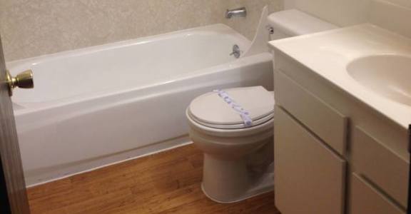 A white toilet sits in a bathroom next to a bathtub.