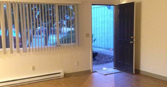A room with a wooden floor and a door leading outside.