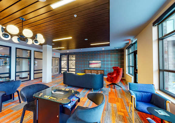 A modern living room with a wooden ceiling and blue chairs at The Bessemer at Seward Commons Apartments, Minneapolis