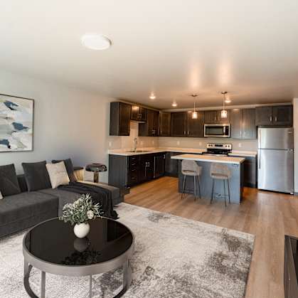 a living room with a couch and a table in front of a kitchen. Fargo, ND Granger Court Apartments .